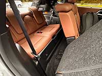 2026-Outlander-PHEV-seating - Sask Valley Voice Cargo area of a car with orange-brown leather rear seats folded down, gray carpeting, and a visible seat belt.